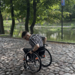 Meżczyzna na wózku na wybrukowanej drodze.